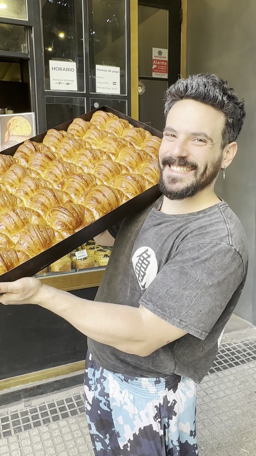 Nicolás con una bandeja de medialunas en la puerta del local
